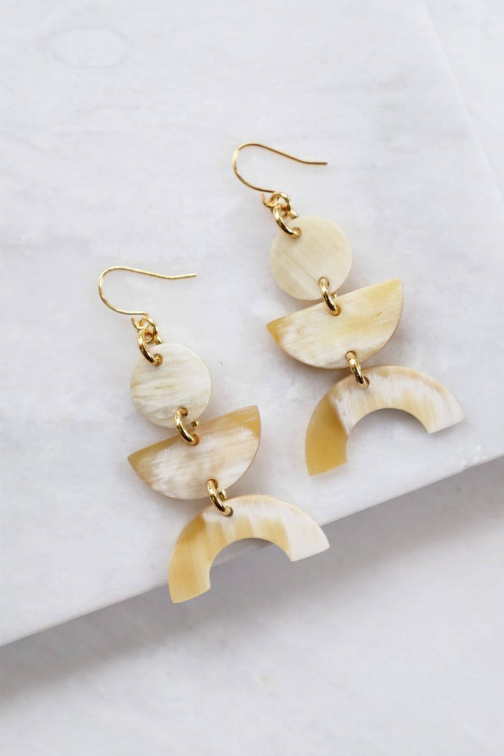 Vui Mung Geometric Buffalo Horn Earrings in light horn with gold-plated hooks, handcrafted and chemical-free, laid on a marble surface.