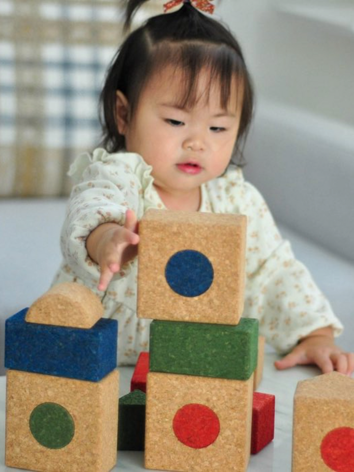 Multi-colored cork building blocks for children scattered on wooden surface showing various shapes and sizes