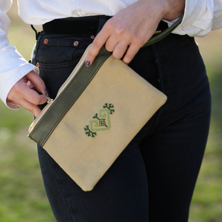 Green heart-shaped leather clutch with traditional Palestinian tatreez embroidery in colorful geometric patterns