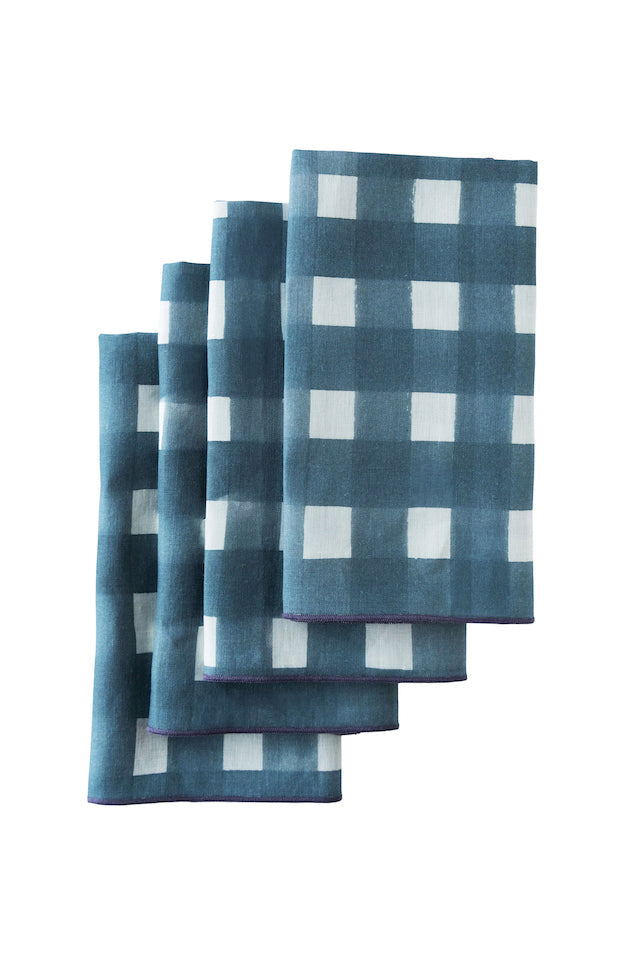Blue cross-hatch linen napkins with painterly brushstroke pattern laid on dining table