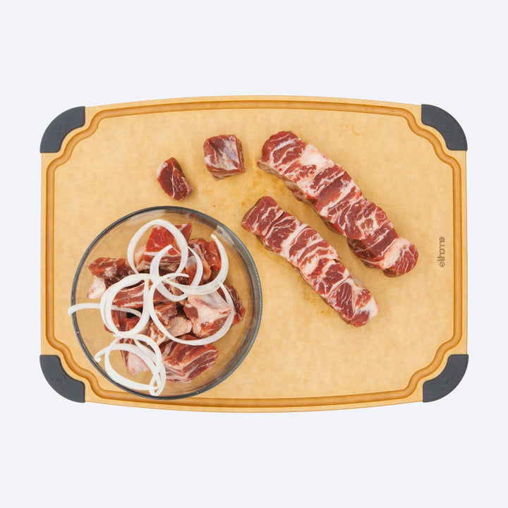 Large reversible cutting board with non-slip feet and juice groove on kitchen counter with vegetables