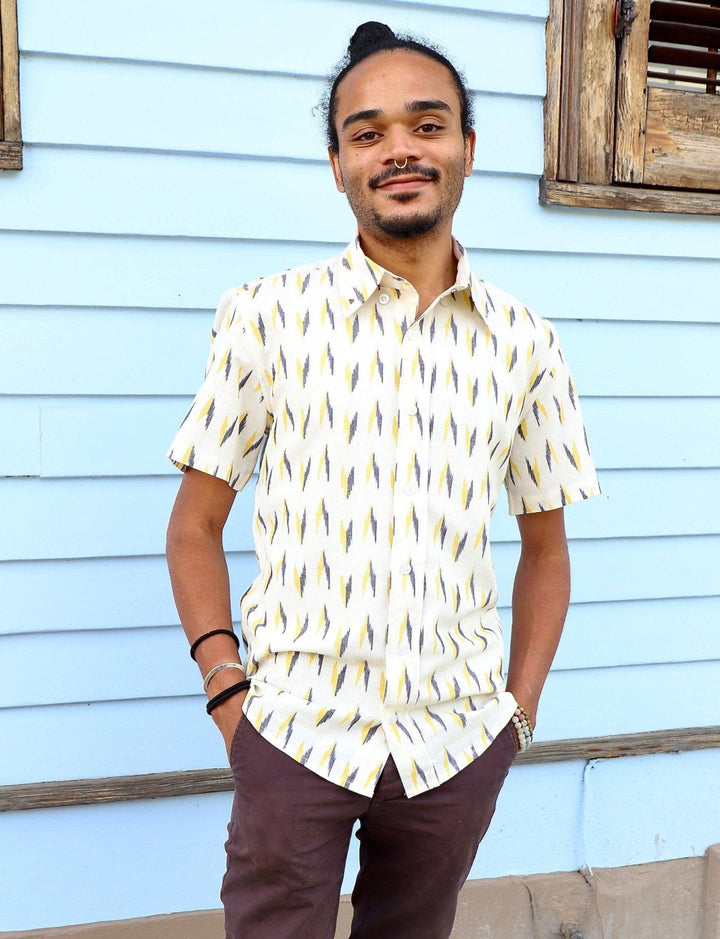 White ikat cotton short sleeve button down shirt with handwoven print pattern laid flat on natural surface