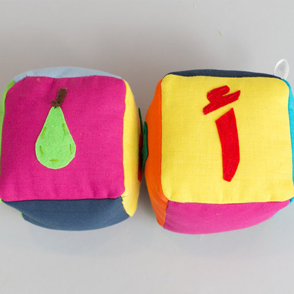 Two fabric blocks with Arabic letters and fruit images for language learning through play
