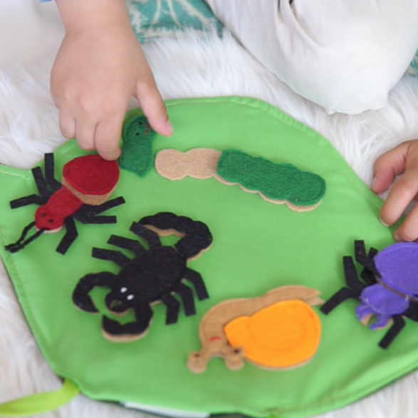 Handmade educational bug puzzle pieces with snail, spider, ant, scorpion and caterpillar on portable fabric mat
