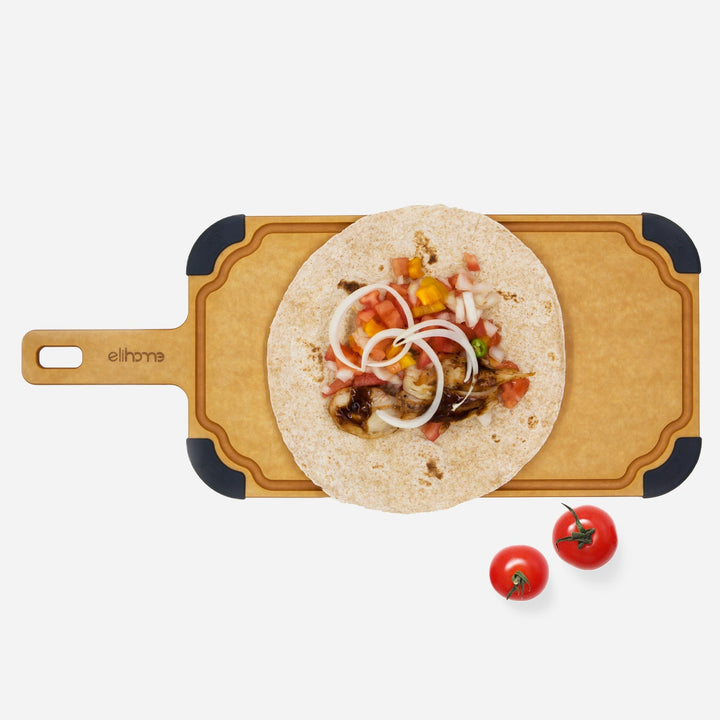 Large wooden cutting board with paddle handle and juice groove on marble kitchen counter