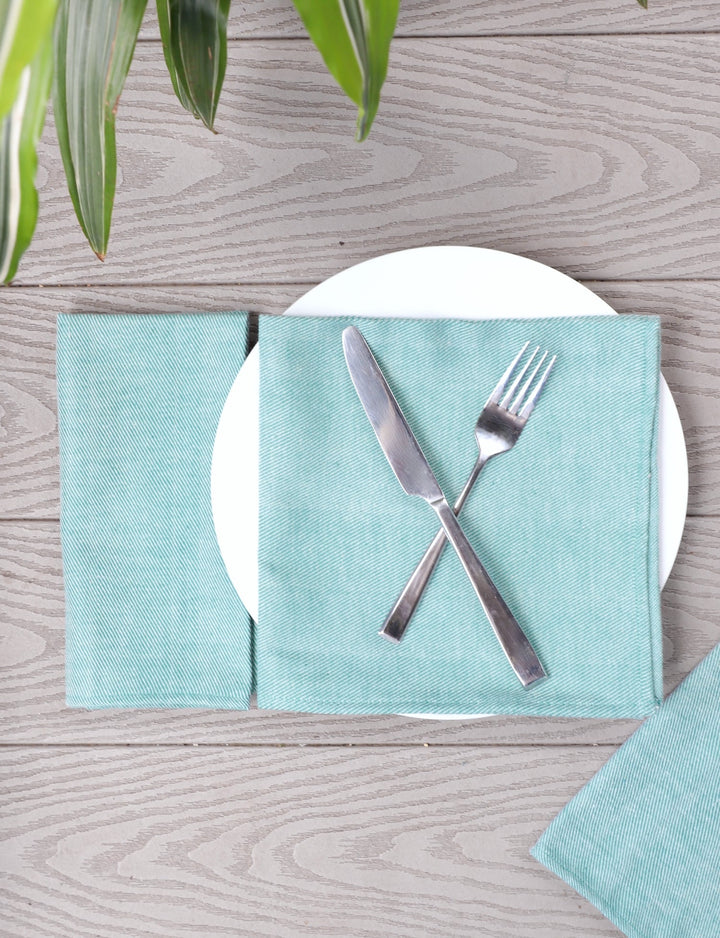 Four mint green handwoven cotton dinner napkins laid flat showing natural texture and gentle color variation