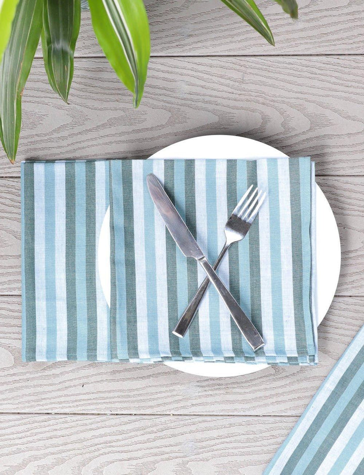 Blue and green striped handwoven cotton napkins set of four arranged on natural wooden table