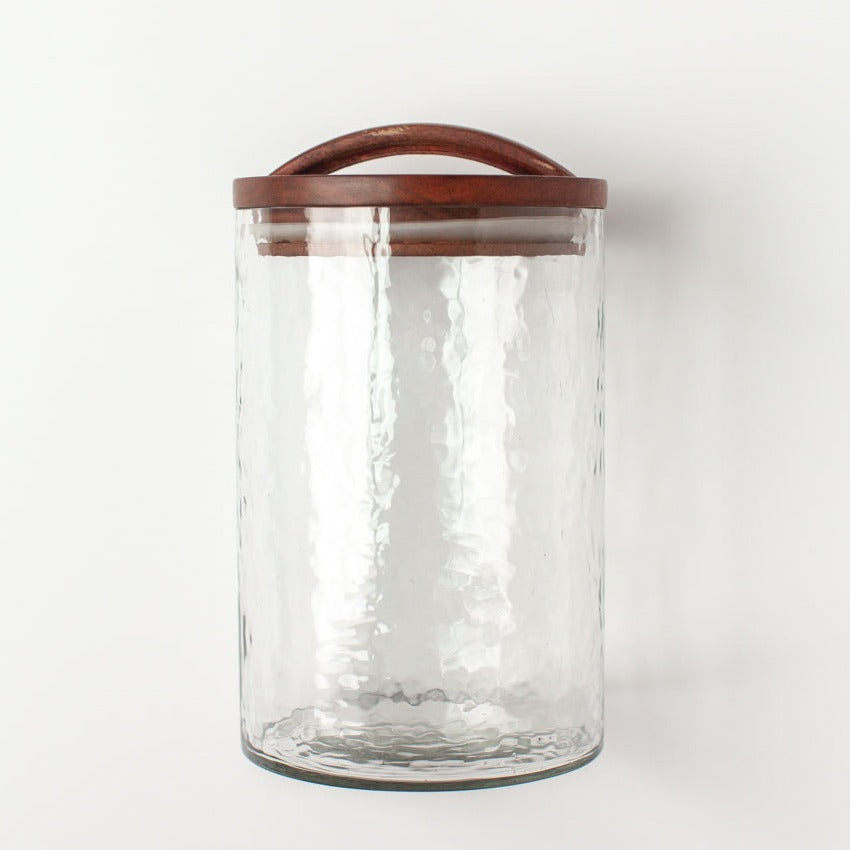 Clear glass canister with hand-carved wooden lid, ideal for kitchen storage or apothecary use. Features an airtight seal. Made in India.