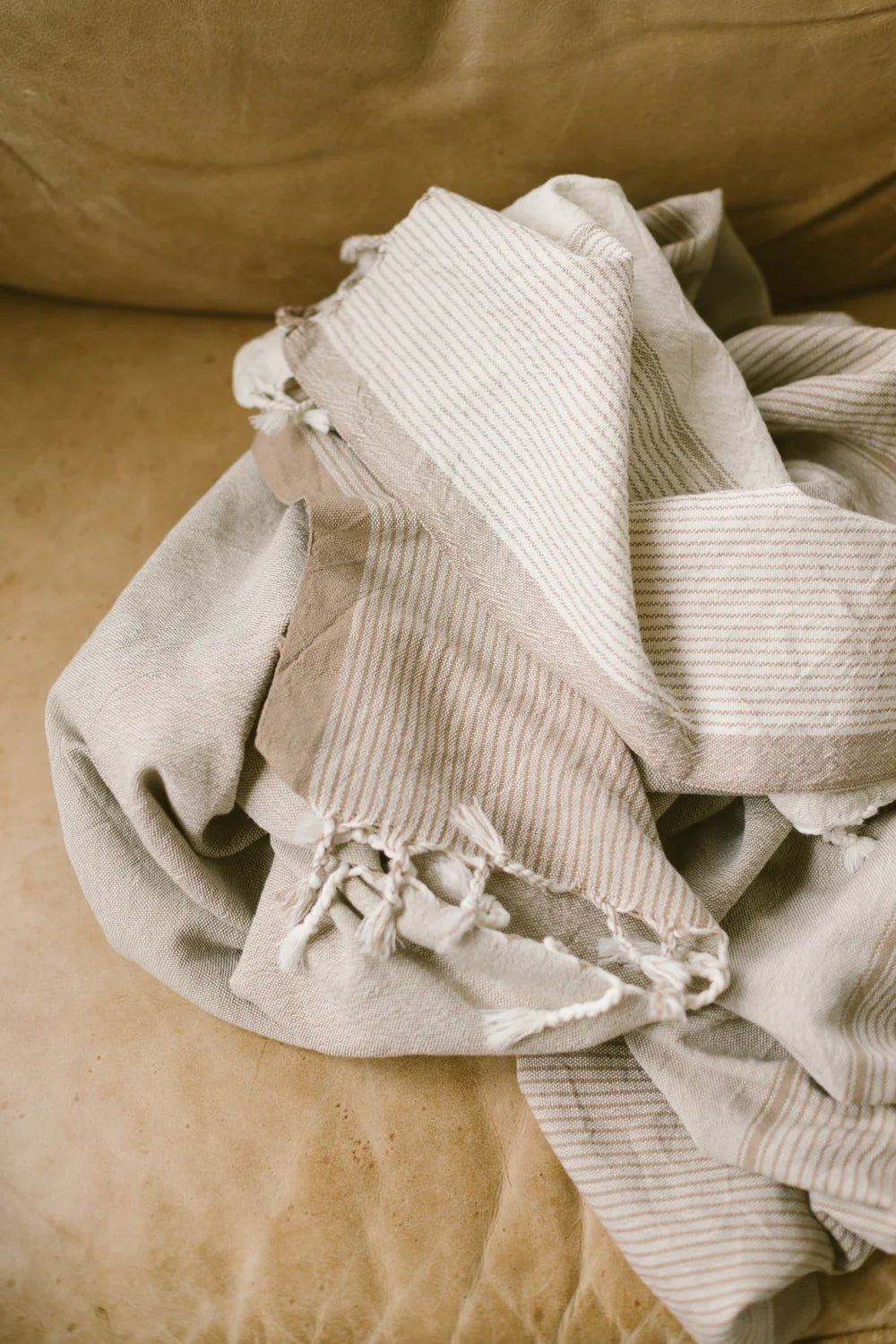 Handwoven Turkish cotton towel in ivory caramel color with traditional tasseled edges laid flat