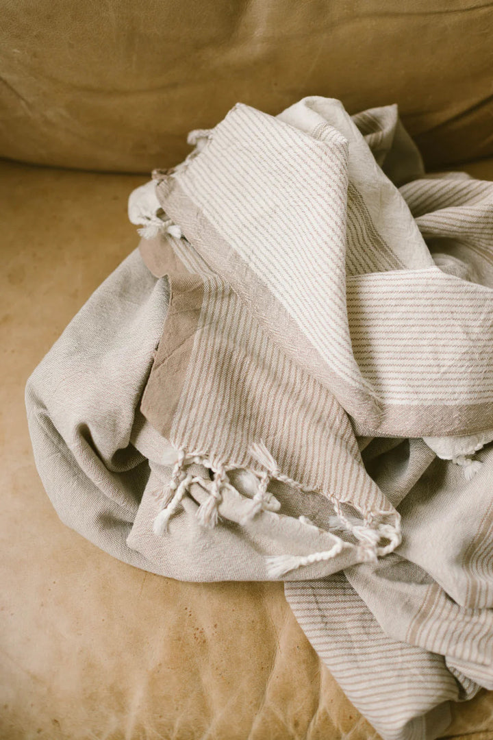 Handwoven Turkish cotton towel in ivory caramel color with traditional tasseled edges laid flat