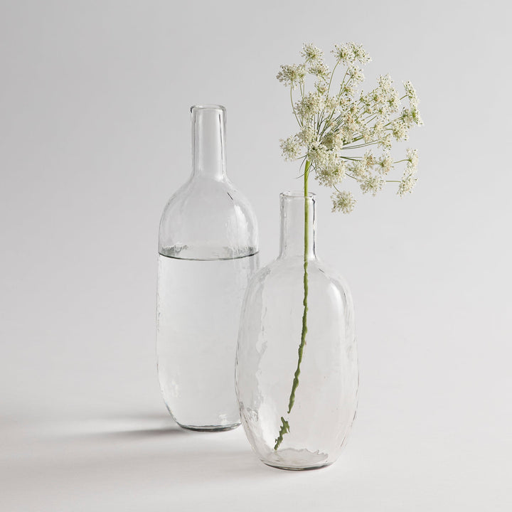 Hand blown pebbled glass bottles set on natural surface showing textured finish and rounded shapes