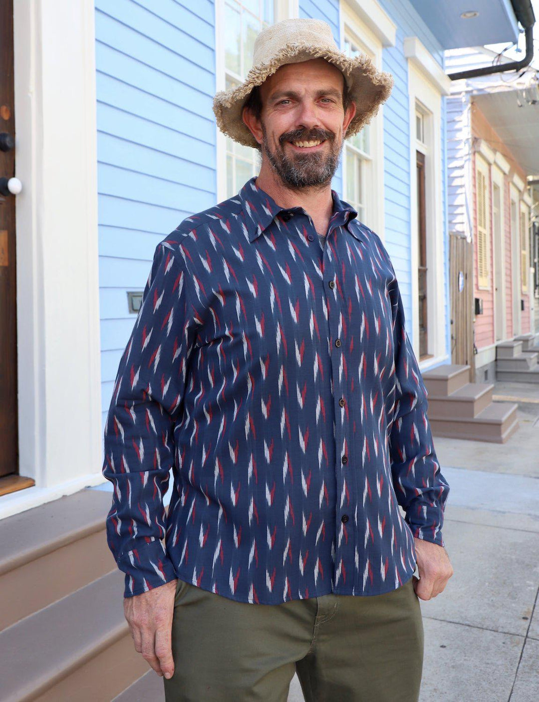 Navy blue organic cotton button down shirt with red and white woven ikat pattern on wooden hanger